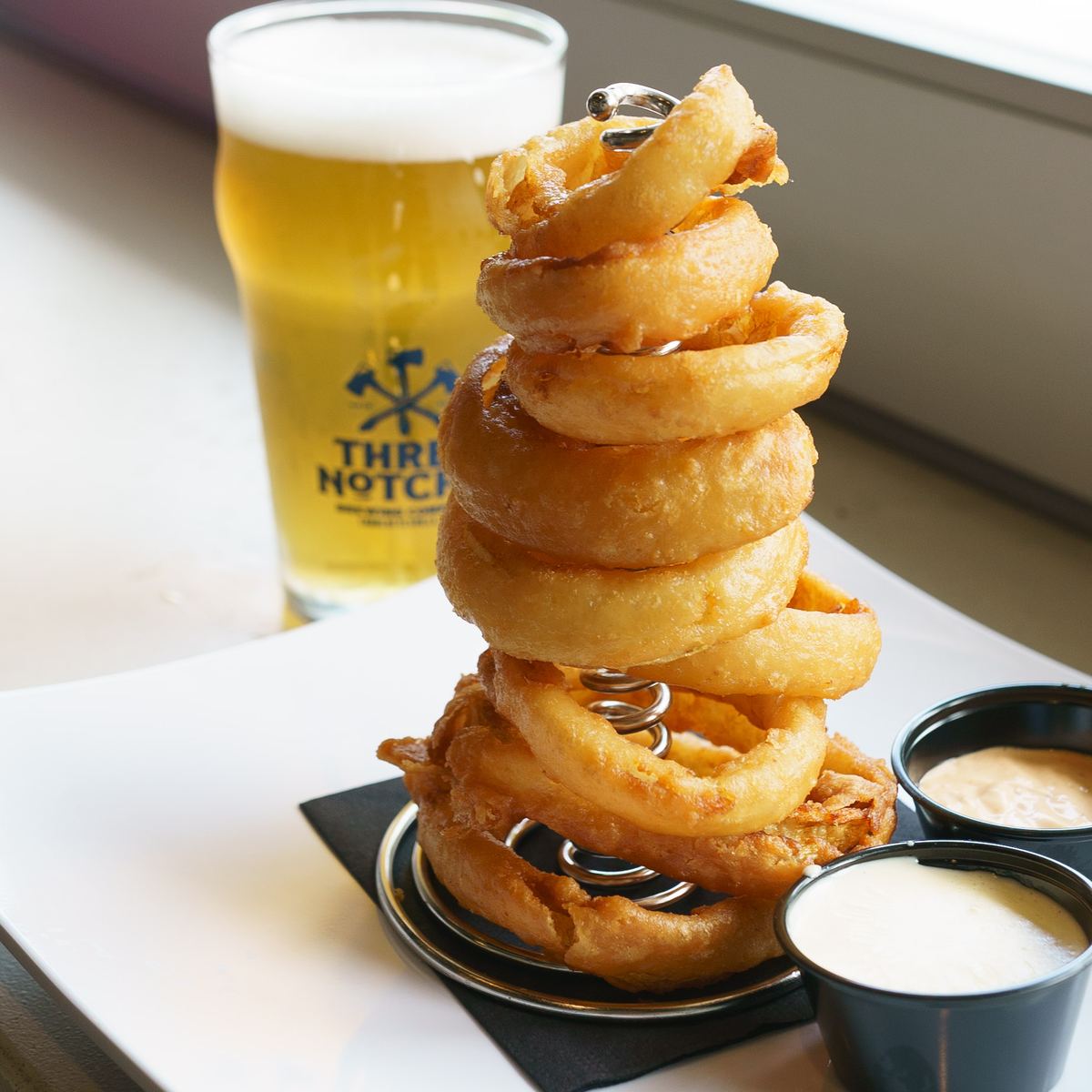 An onion-ring tower beside a Three Notch'd pint